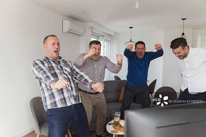兴奋的男人们正在庆祝电视上篮球比赛的积极结果图片素材