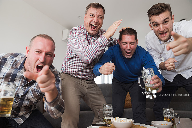 男子观看体育赛事时兴奋地欢呼并喝啤酒图片素材