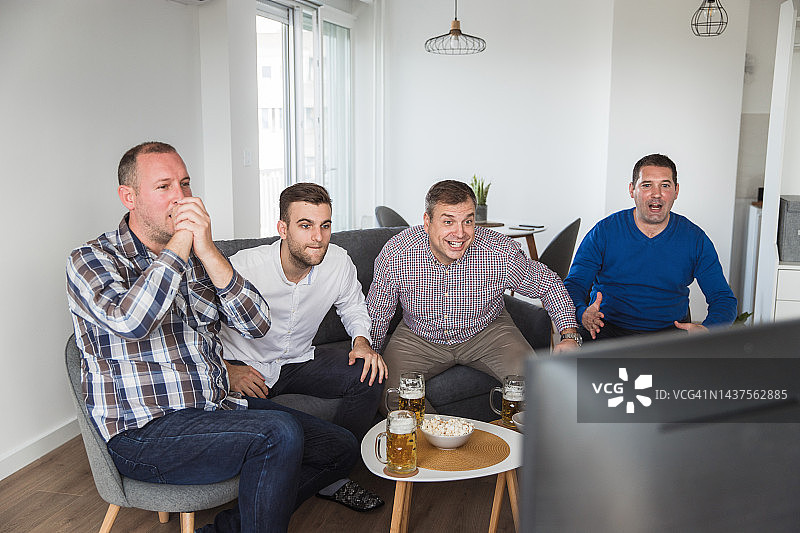 焦急但面带微笑的男人们等待足球比赛结果图片素材