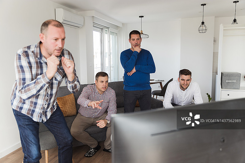 忧虑的男人们在电视上看体育直播图片素材