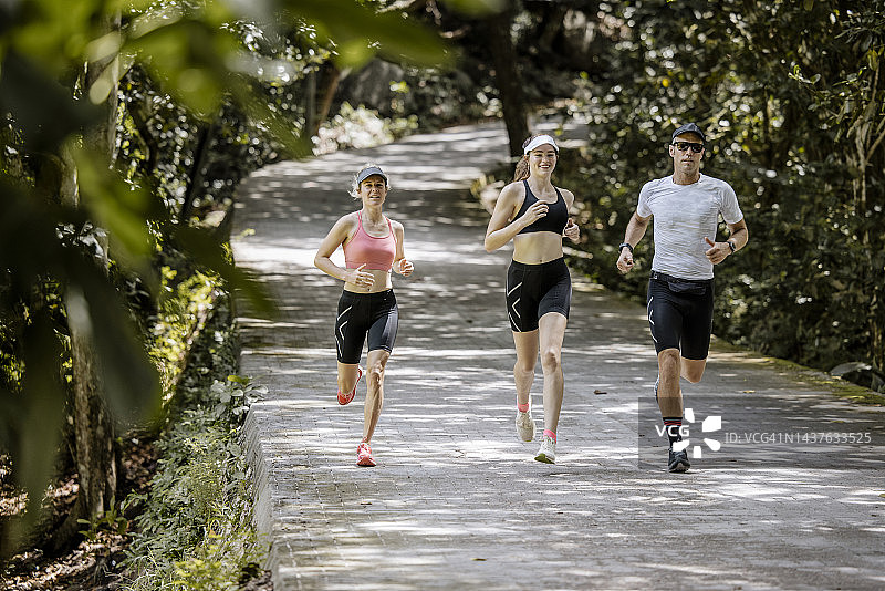 朋友们在绿树成荫的丛林小道上奔跑图片素材