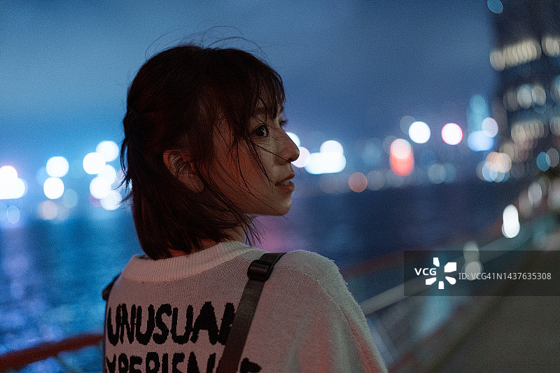年轻亚洲女性在街头欣赏城市夜景图片素材