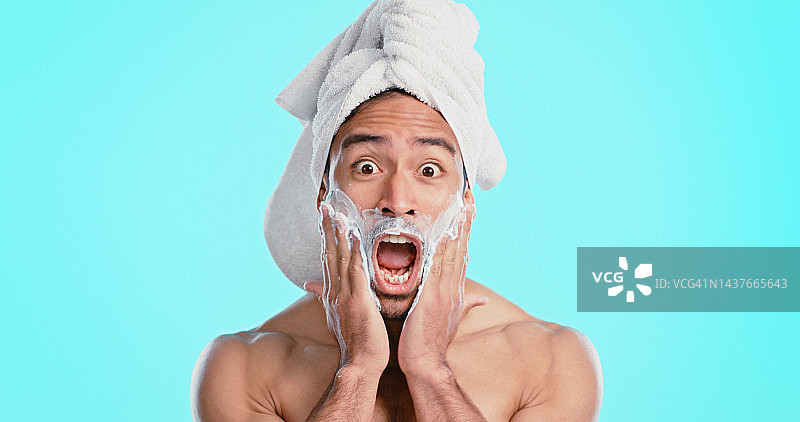 惊喜，剃须膏和男人，健康、护肤和蓝色工作室背景，兴奋、毛巾或震惊，肖像，哇和年轻男人用面部乳液进行身体护理和疯狂图片素材