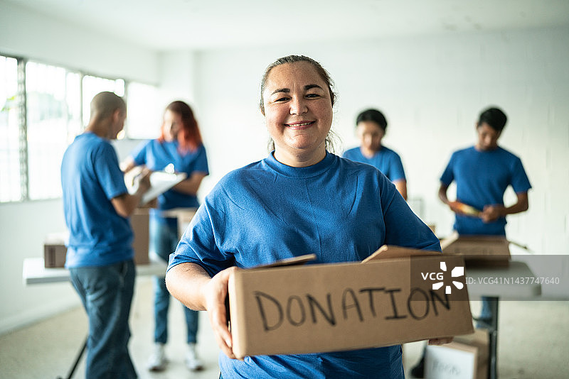 中年女志愿者手持捐款箱的肖像照图片素材