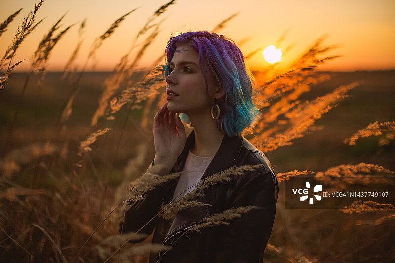 夕阳背景下的蓝色头发夹克女人图片素材