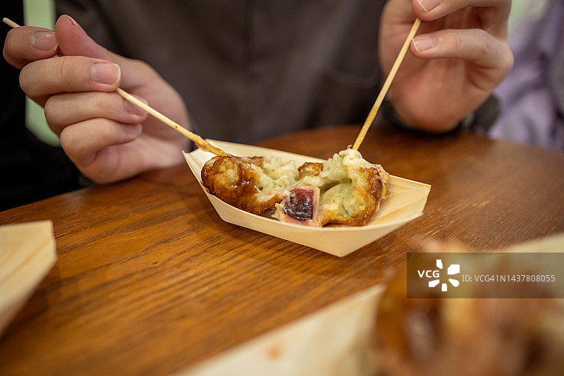 亚洲游客吃章鱼小丸子特写图片素材