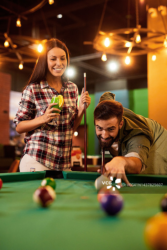 快乐的年轻夫妇在台球厅一起打台球图片素材