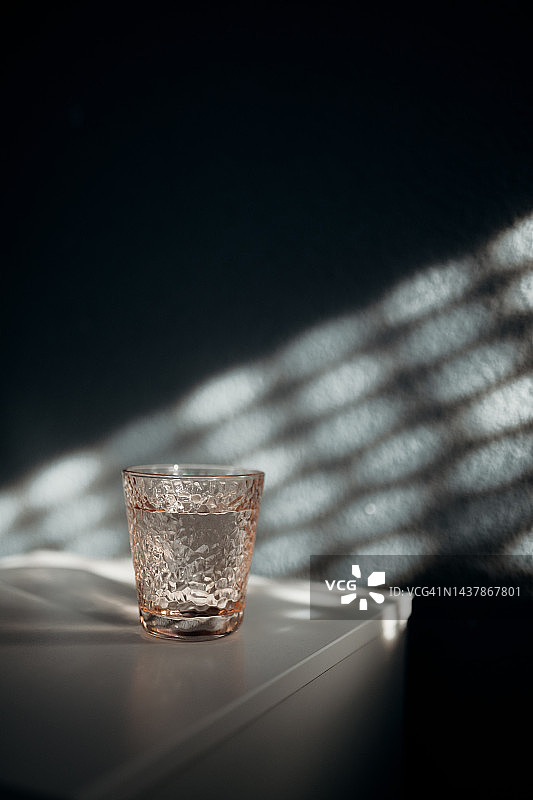 阳光洒入房间，床头柜上的玻璃杯水图片素材