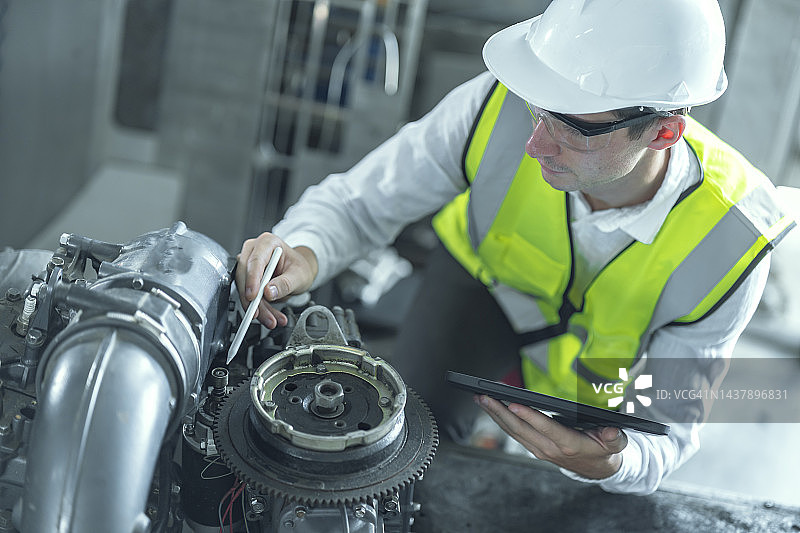 俯视：男工程师用平板电脑维修引擎图片素材
