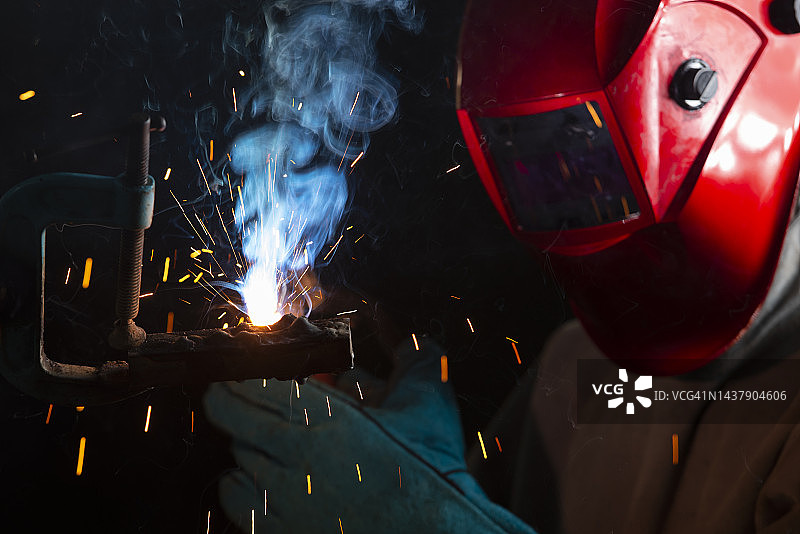 焊接工人在钢铁行业工作，佩戴安全面罩和手套图片素材