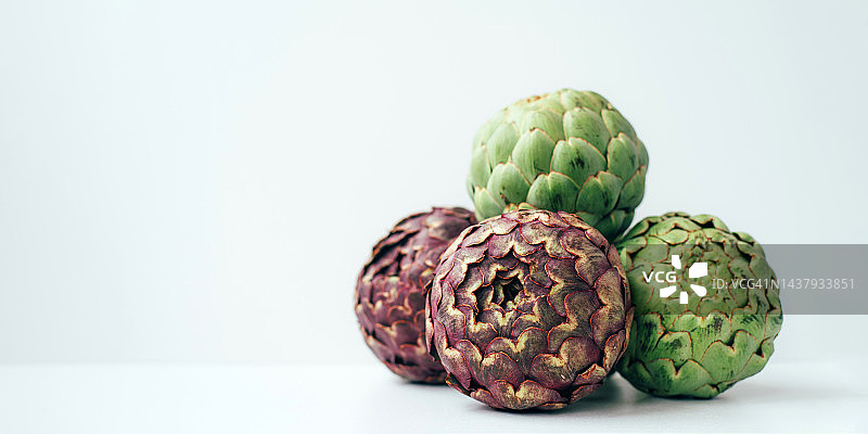 白色背景上的许多紫色和绿色朝鲜蓟，异国情调的蔬菜，健康食品，农场收获，菜肴配料图片素材