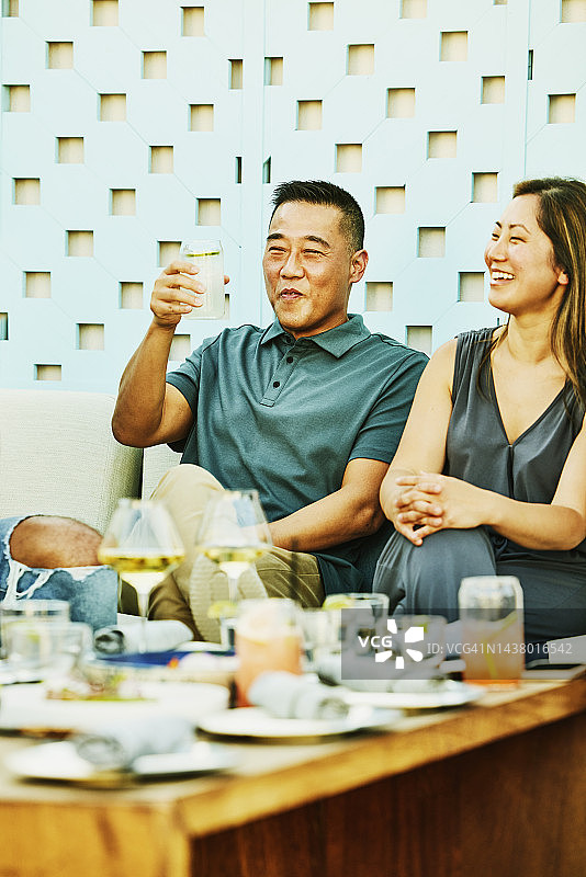 微笑的夫妇在户外餐厅与朋友敬酒图片素材