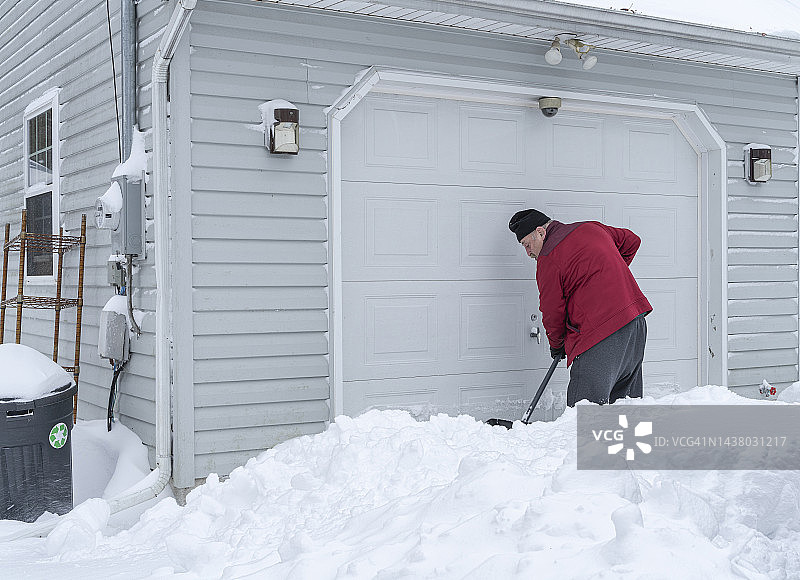 年长的男人在车库前铲雪图片素材