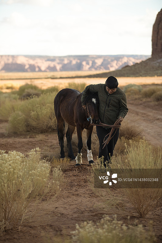 在纪念碑谷与马行走的纳瓦霍男孩图片素材