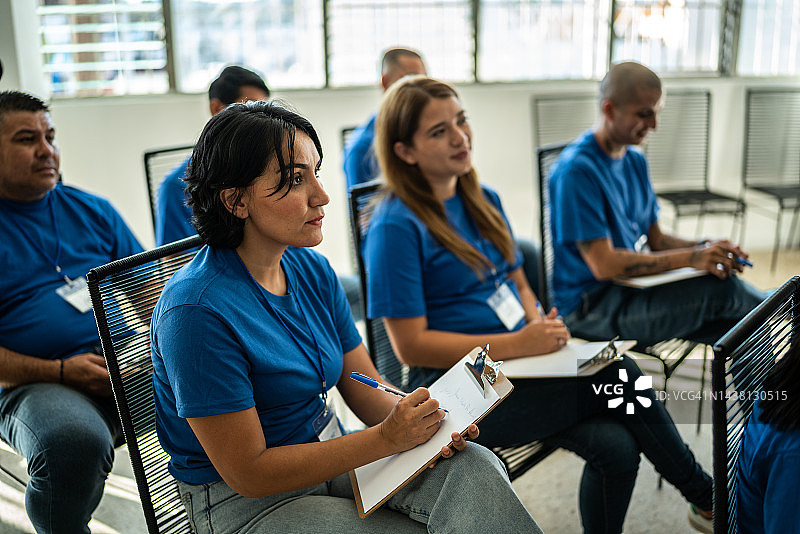 中年妇女在社区中心（或公司会议）的写字板上做注释图片素材