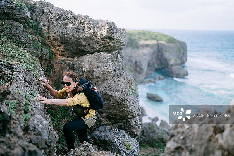 从日本海滩攀登岩石峭壁的女人图片素材
