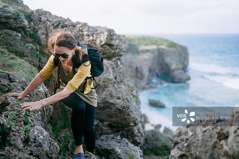 从日本海滩攀登岩石峭壁的女人图片素材