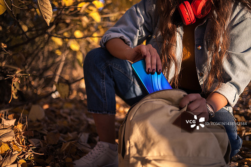 女人将手机放入背包图片素材