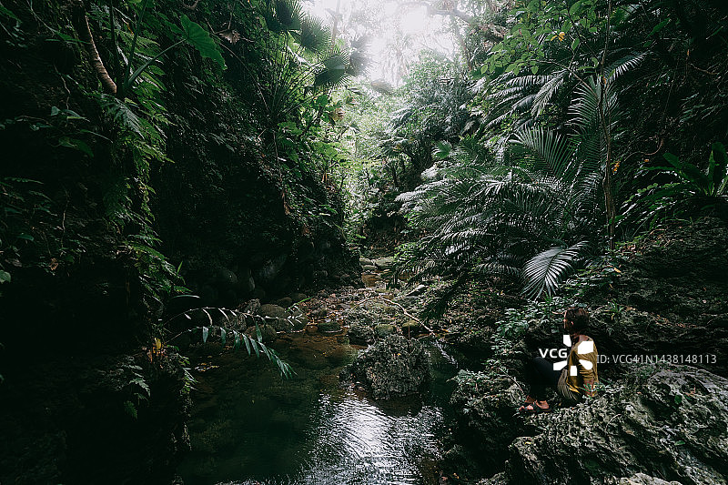 女人在雨林徒步旅行时在溪边休息图片素材