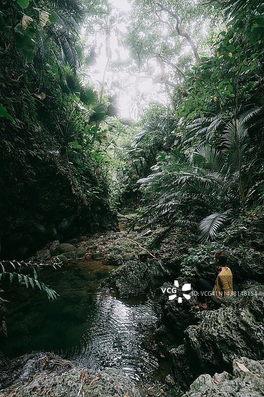 女人在雨林徒步旅行时在溪边休息图片素材