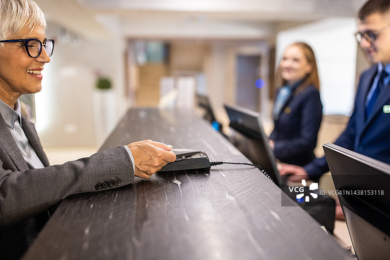女商人在酒店前台用信用卡支付图片素材