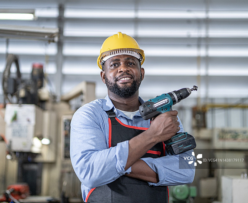 在制造工厂使用螺旋钻的非裔美国技术员图片素材
