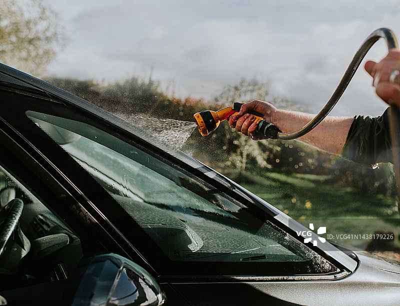 男人用水管清洗汽车图片素材