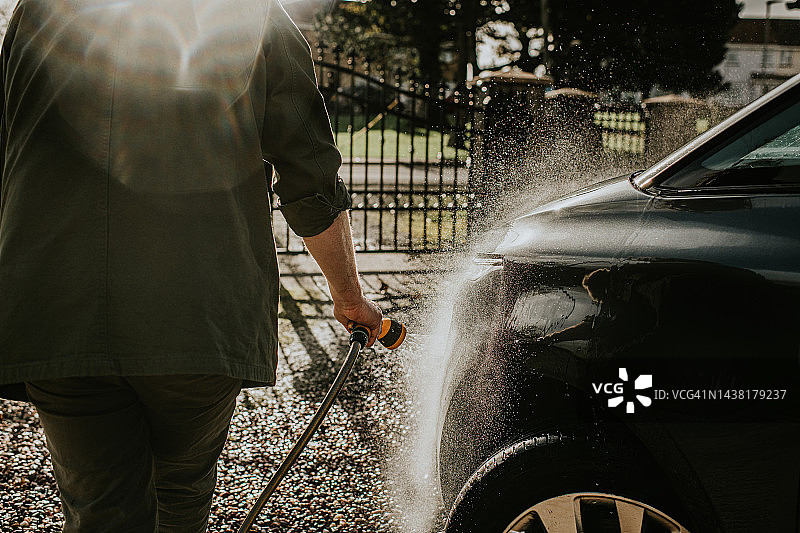 男人用水管清洗汽车图片素材
