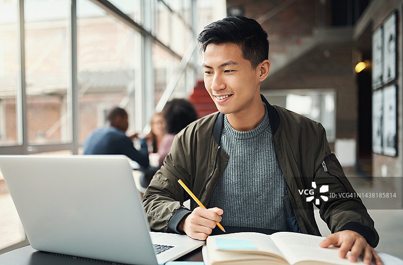 在校园里用笔记本电脑学习的亚洲男大学生图片素材
