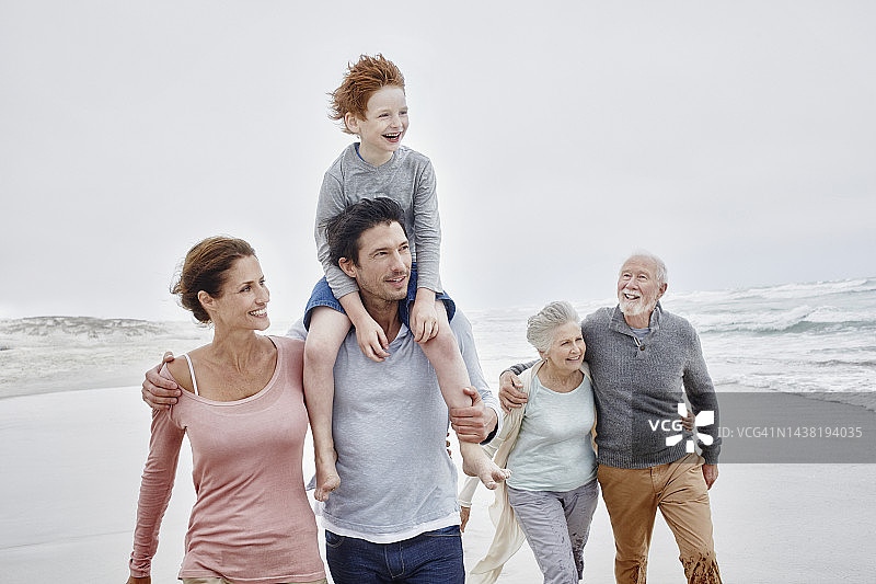 幸福夫妇与儿子和祖父母在海滩共度美好时光图片素材