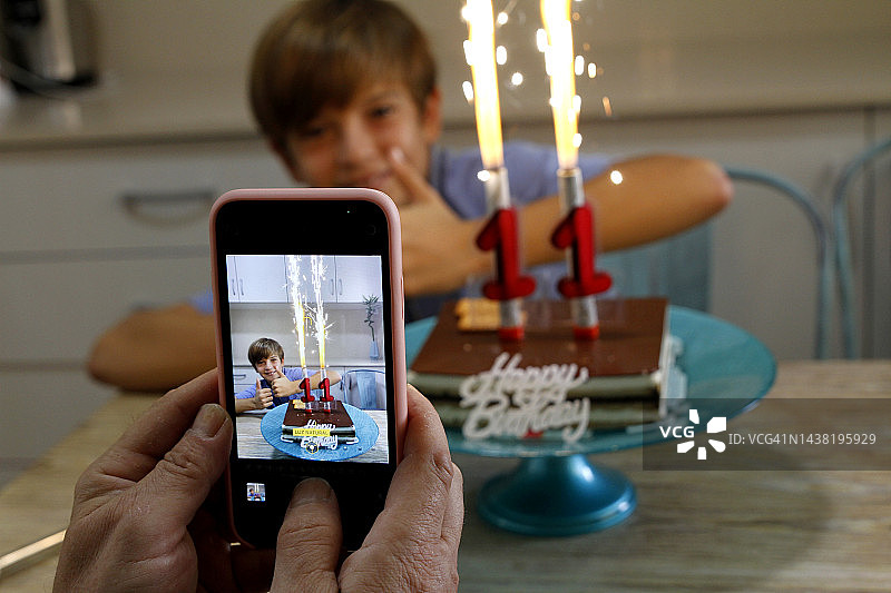 男人在生日派对上拍摄儿子图片素材