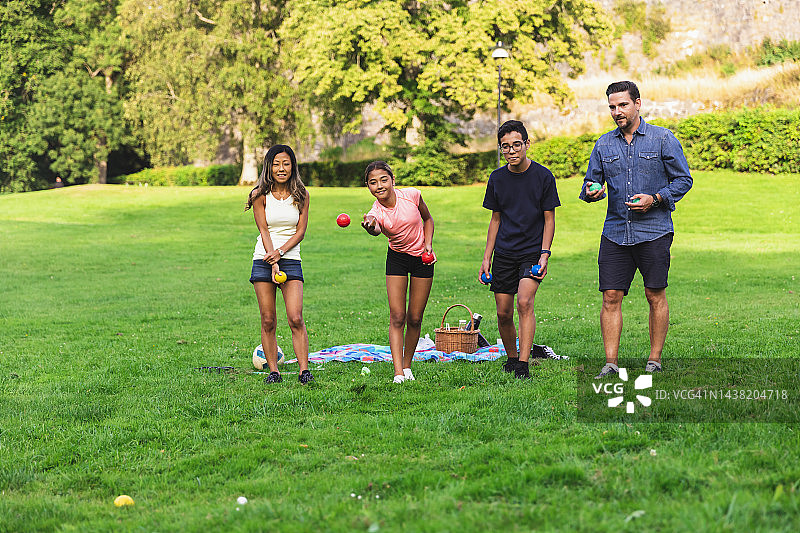 多民族家庭在草坪上玩滚球游戏图片素材