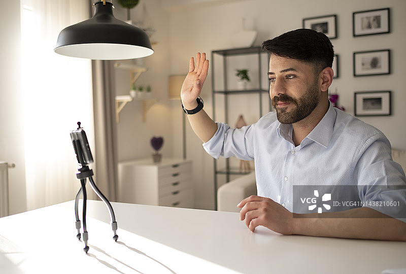 坐在沙发上用智能手机交流的年轻男人图片素材