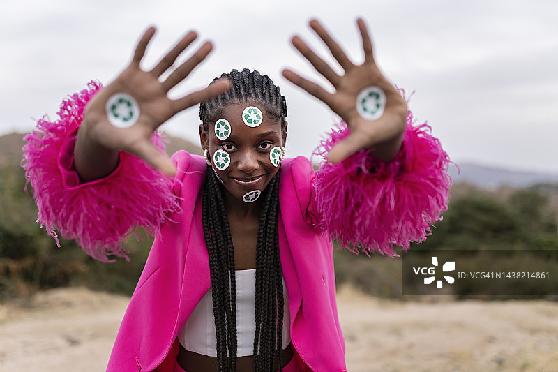 微笑的年轻女子脸上和手上贴着回收符号贴纸图片素材