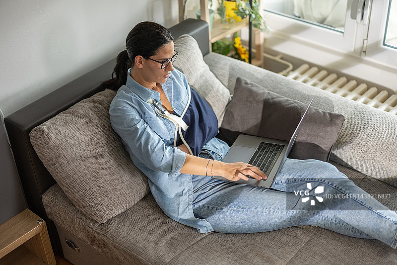 手臂受伤的妇女使用笔记本电脑图片素材