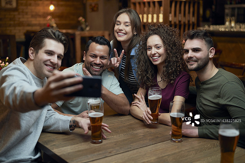 在酒吧里喝啤酒和自拍的快乐朋友们图片素材