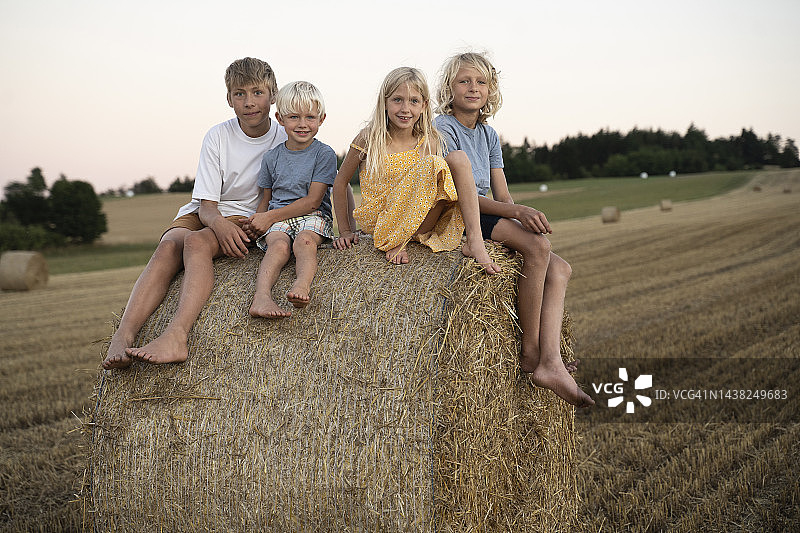 笑容满面的男孩和女孩坐在干草堆上图片素材