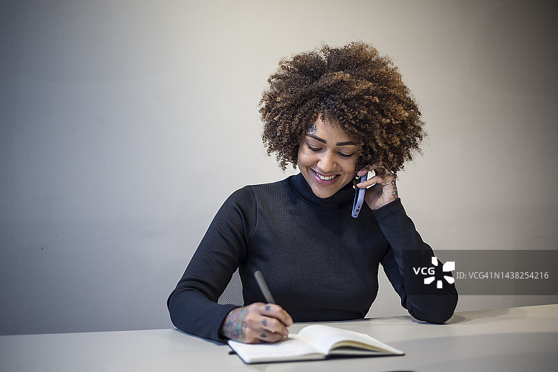 在办公室用手机交谈和写作的黑人妇女图片素材