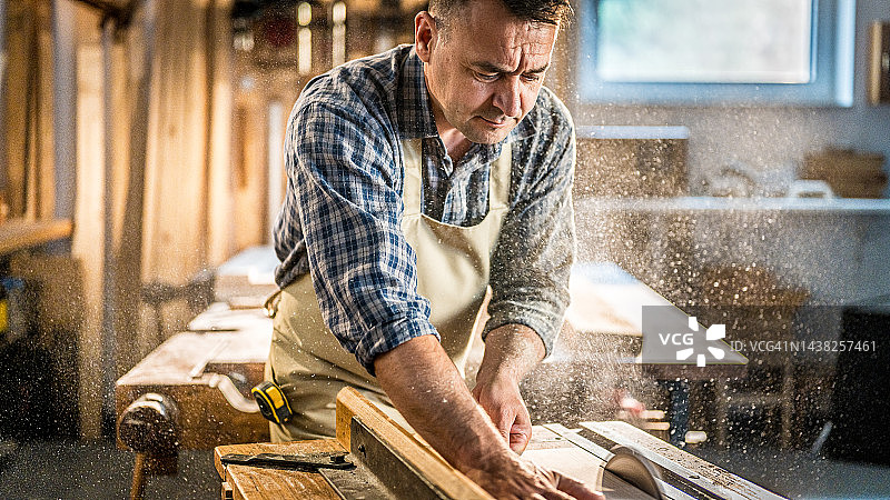 经验丰富的木匠用圆锯切割木材图片素材