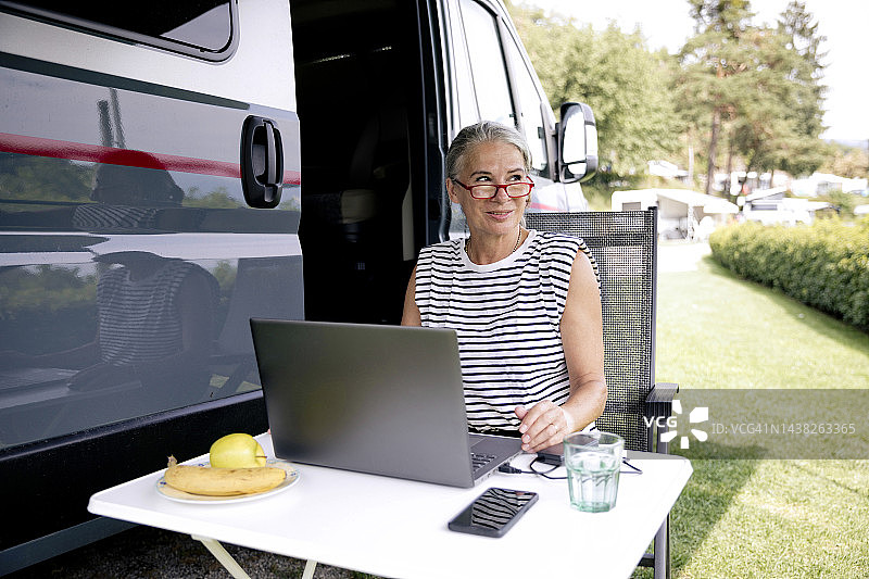 年长的自由职业者坐在货车旁使用笔记本电脑图片素材