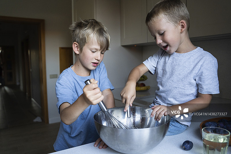 兄弟在家里的厨房里搅拌蛋糕面糊图片素材
