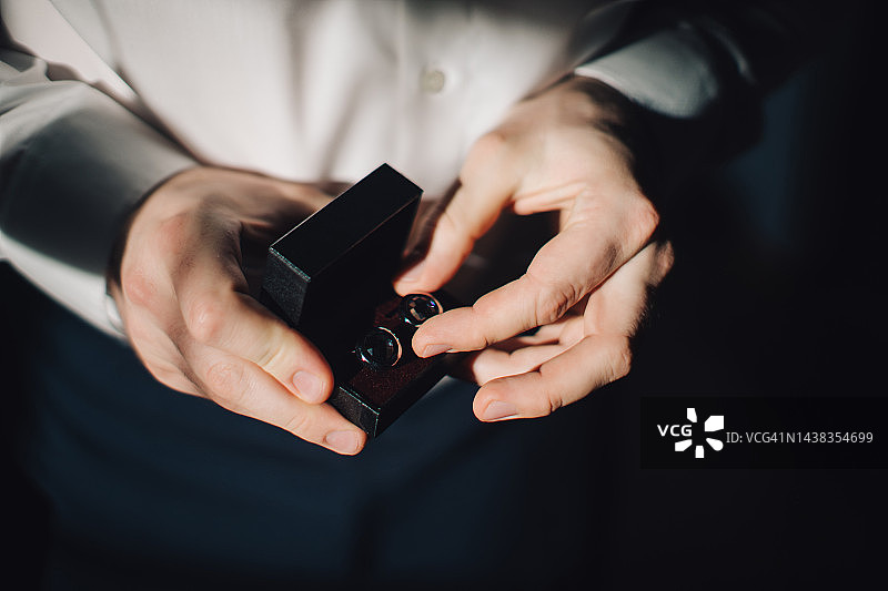 两只手拿着黑色盒子里的袖扣图片素材