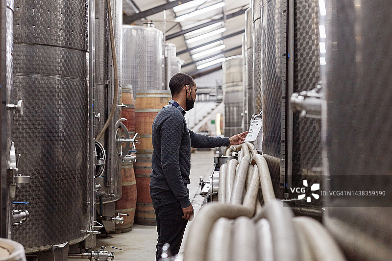 葡萄酒生产：酒窖中一名黑人男子在酿酒厂发酵图片素材