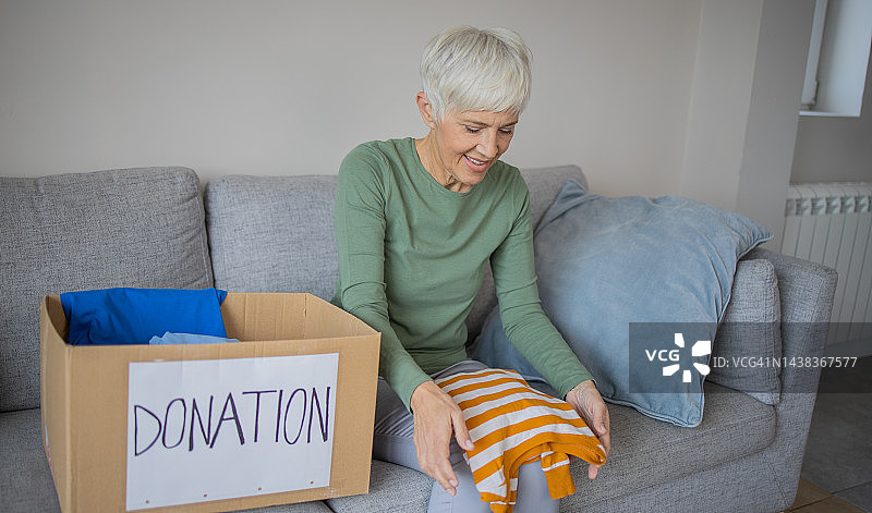 年长的女人整理衣物并打包捐赠箱图片素材