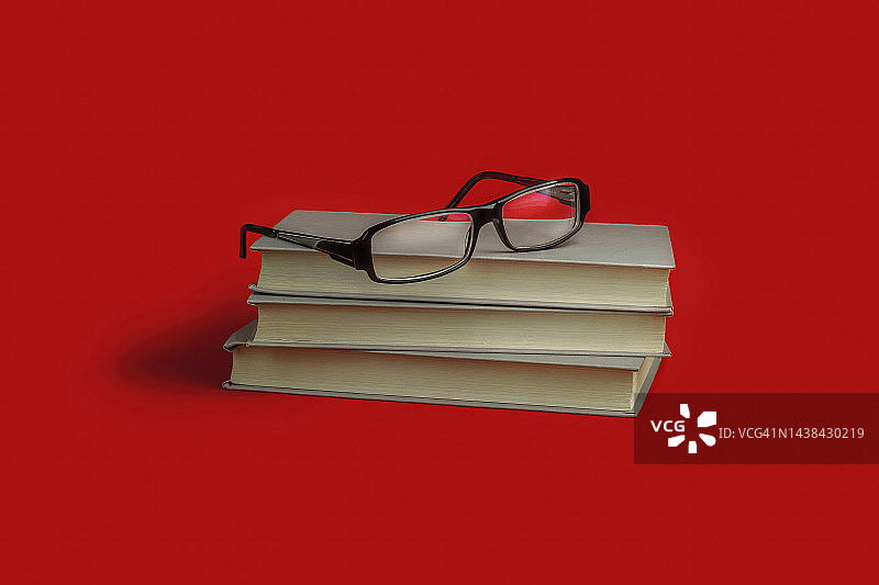 书堆和红背景上的眼镜，学生与教育图片素材