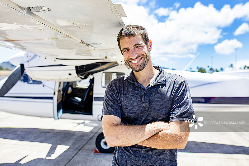 年轻飞行员与私人螺旋桨飞机合影图片素材