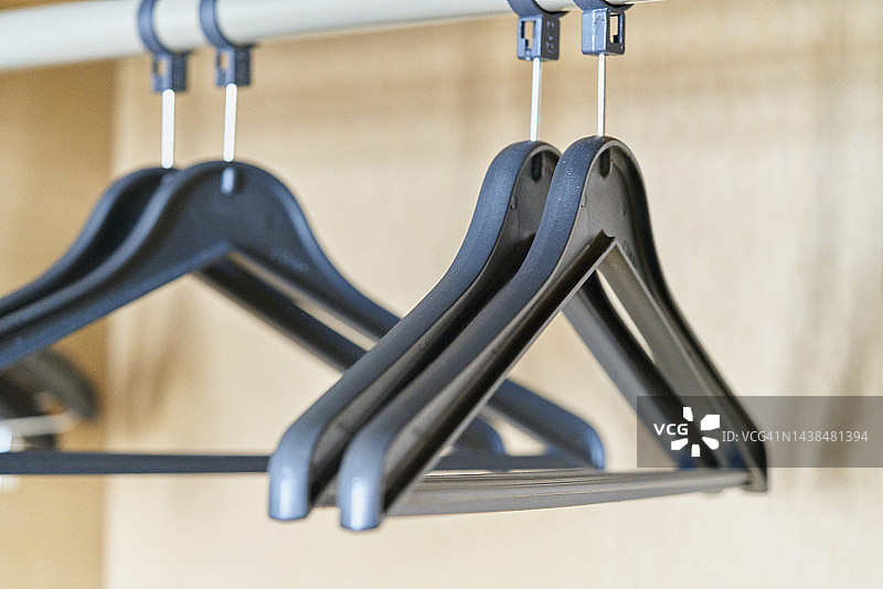 木柜内悬挂在细金属管上的四个黑色衣架图片素材