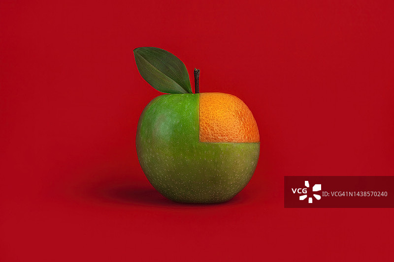 红色背景上的青苹果和橘子瓣，返现概念图片素材