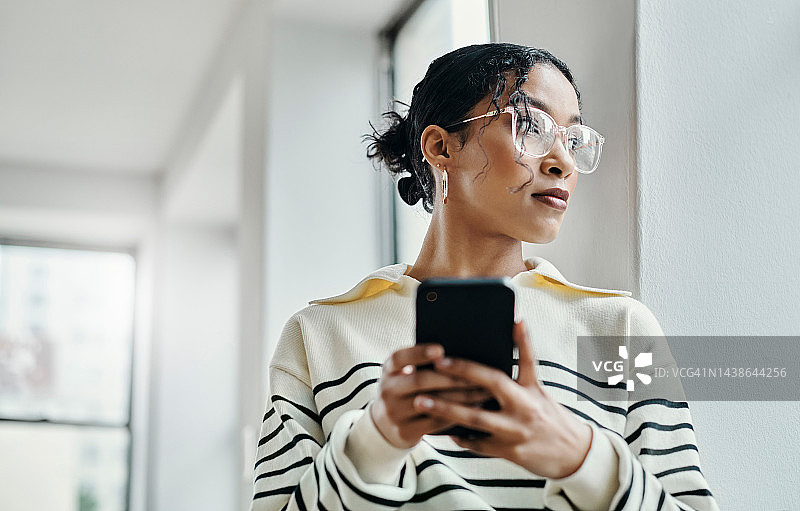 在窗边思考的商务女性，制定数字营销策略、品牌增长创新或广告创意。在办公室使用移动技术的创意工作者、设计师或职员图片素材