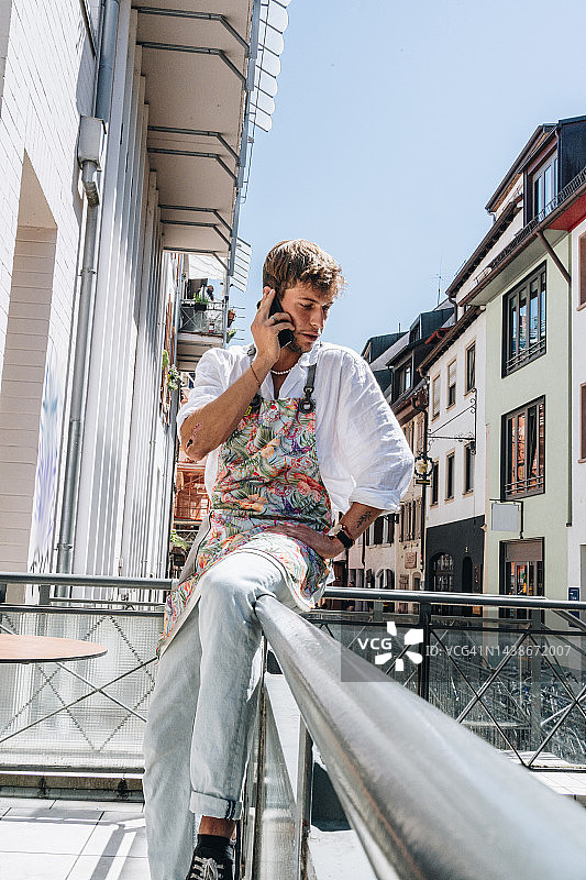 咖啡师在露台上放松，用手机交谈图片素材